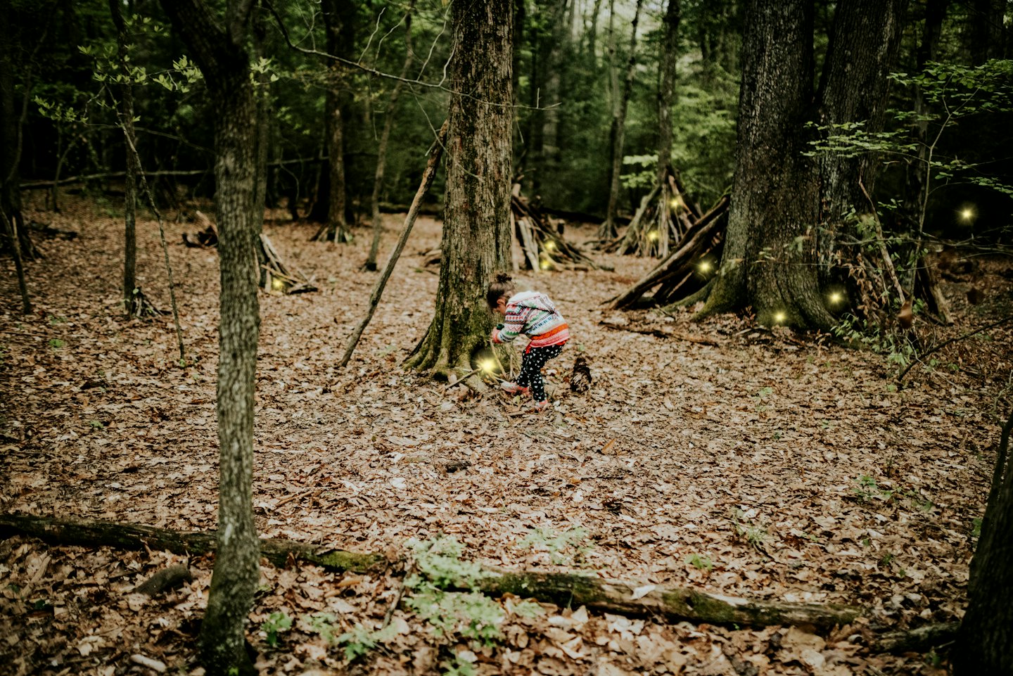 Kind erkundet einen magischen Wald mit leuchtenden Lichtern.
